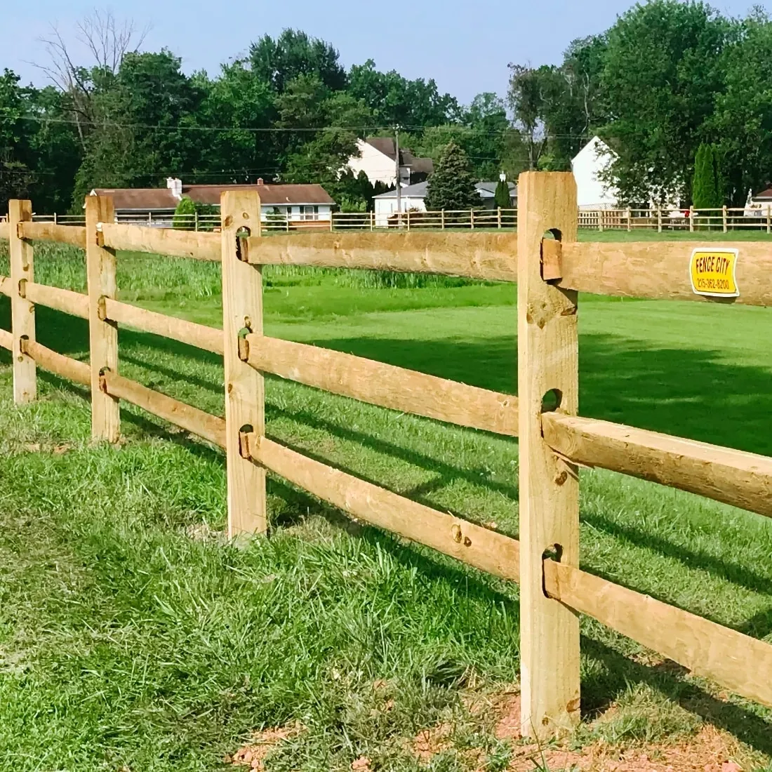 Wooden barrier beside lush field
